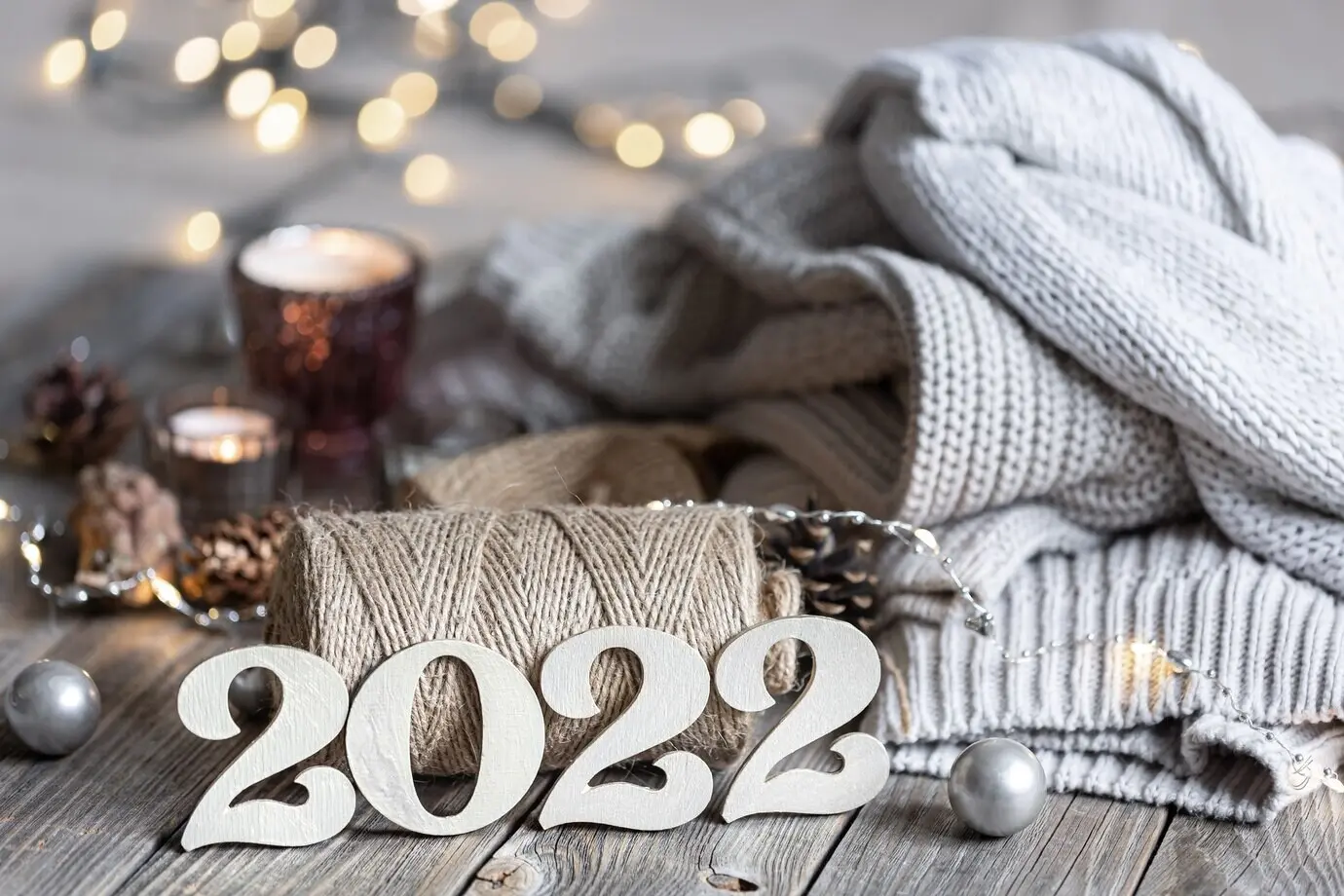 Gemütliche Neujahrskomposition mit dekorativen 2022-Zahlen, gestrickten Elementen und Bokeh-Lichtern.
